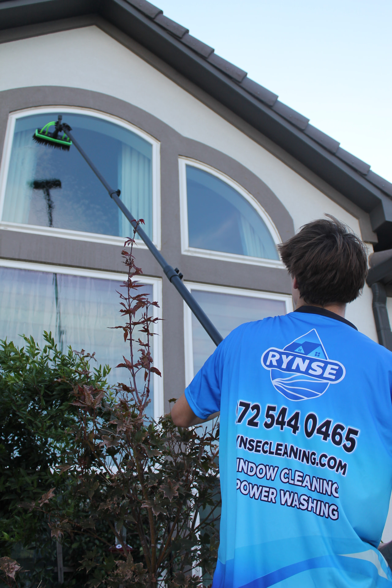RYNSE technician cleaning upper-story windows at a North Texas home